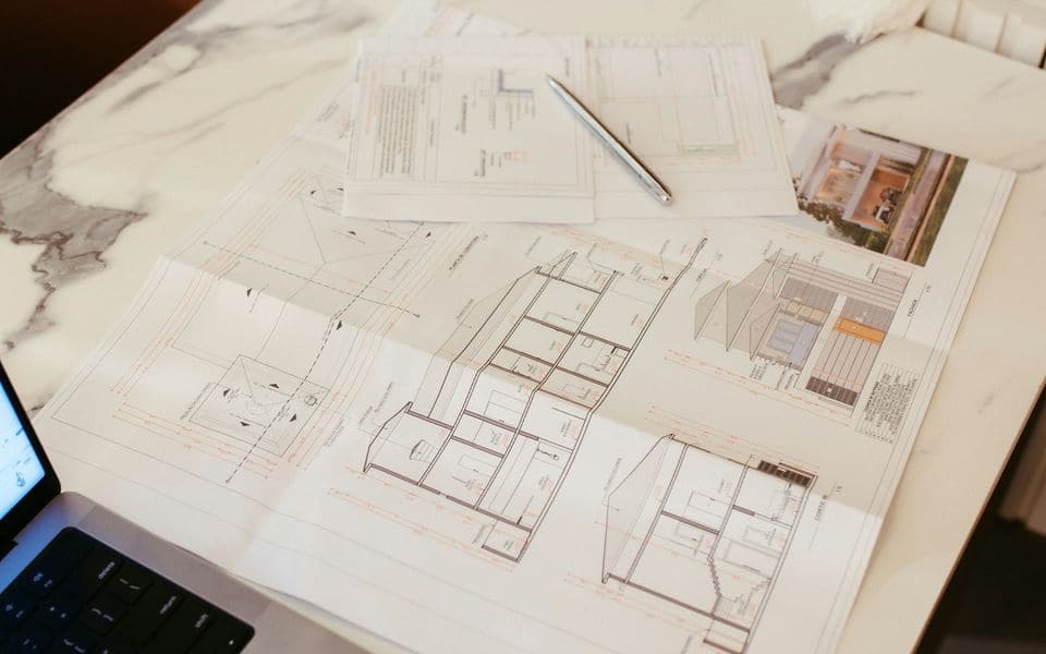 Architectural drawings and a laptop on a marble desk